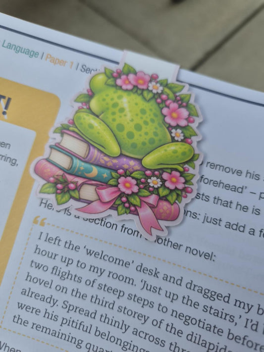 Back of floral frog magnetic bookmark sitting on colourful books
