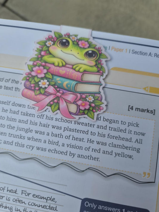 Cute floral frog magnetic bookmark sitting on colourful books